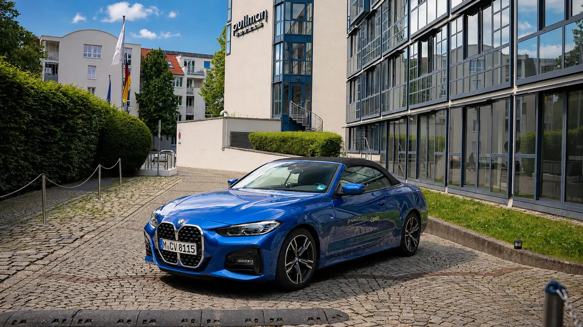 Blauer BMW 4er Cabrio von vorne vor Hoteleingang geschlossenes Verdeck