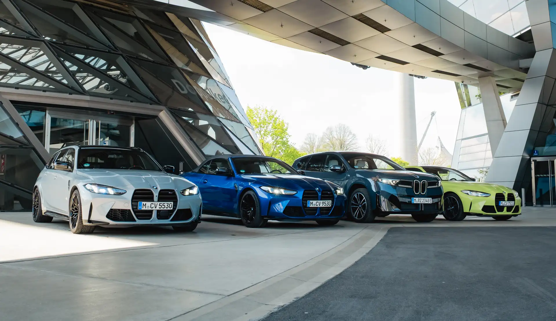 BMW iX3, BMW M4, BMW M3 Touring und ein weiterer BMW M4 vor der BMW Welt in München als Teil des CarVia Premium Carsharing Angebots.