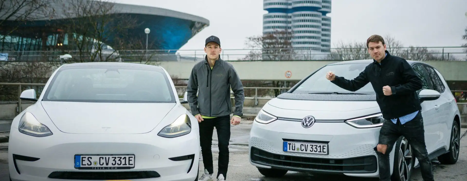 CarVia-Gründer Julian und Joschka Reik mit einem weißen Tesla Model 3 und einem VW ID. 3. 